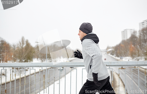 Image of man running along snow covered winter bridge road