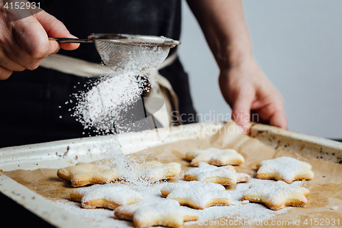 Image of Person covering cookies with powdered sugar