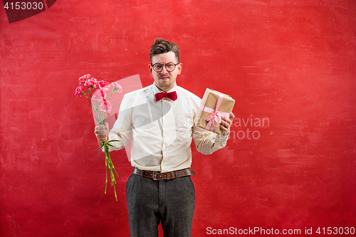 Image of Young funny man with flowers and gift