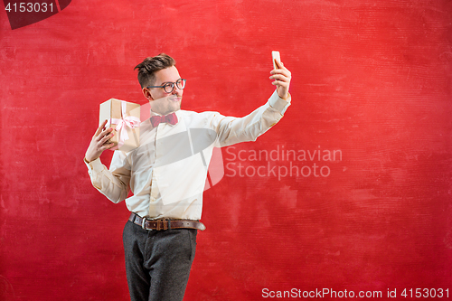 Image of Young beautiful man with gift and phone