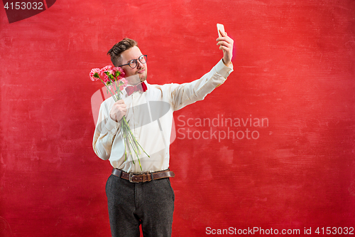 Image of Young beautiful man with flowers and phone
