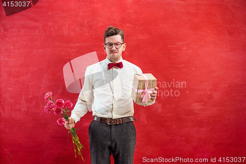 Image of Young funny man with flowers and gift