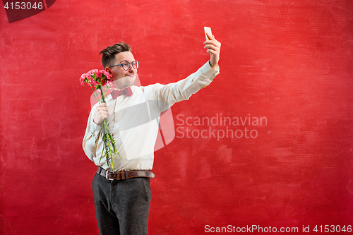 Image of Young beautiful man with flowers and phone