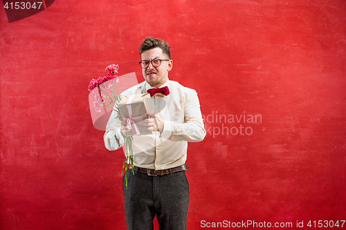 Image of Young funny man with flowers and gift