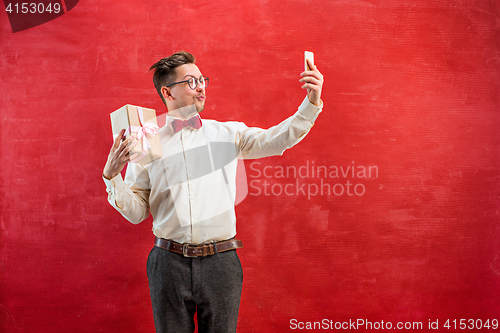 Image of Young beautiful man with gift and phone