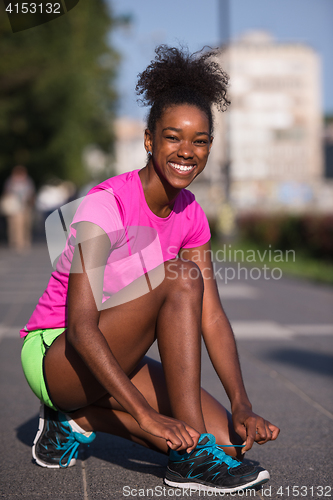 Image of African american woman runner tightening shoe lace