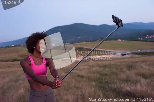 Image of black woman photographing herself in nature