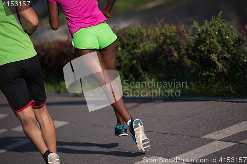 Image of young smiling multiethnic couple jogging in the city