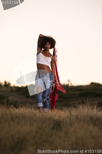 Image of black girl dances outdoors in a meadow
