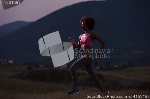 Image of Young African american woman jogging in nature