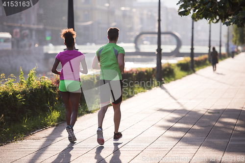 Image of young multiethnic couple jogging in the city