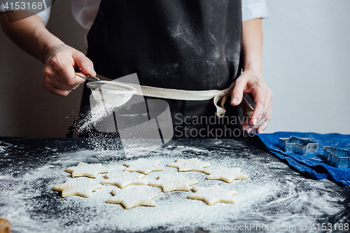 Image of Person putting raw cookies to flour