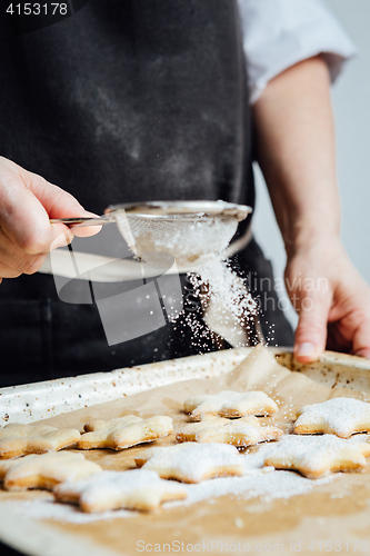 Image of Person covering cookies with powdered sugar