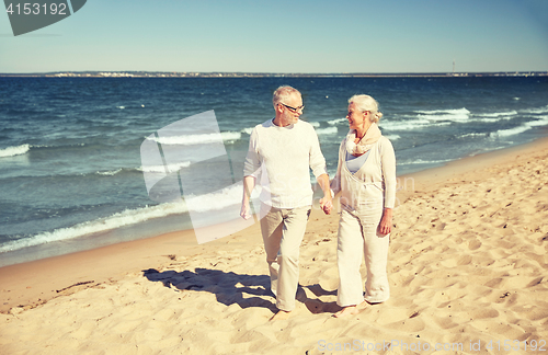 Image of happy senior couple walking along summer beach