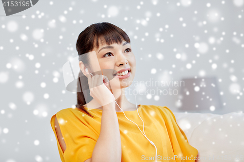 Image of happy asian woman with earphones listening music