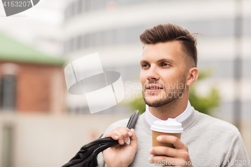 Image of young man with bag drinking coffee in city