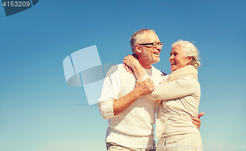 Image of happy senior couple hugging outdoors