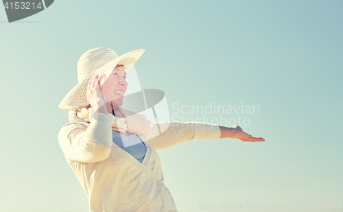 Image of happy senior woman in sun hat over blue sky