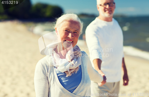 Image of happy senior couple holding hands on summer beach