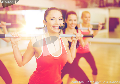 Image of group of smiling people working out with barbells