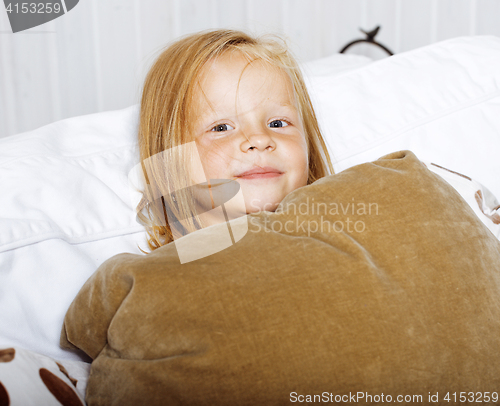 Image of little cute blonde norwegian girl playing on sofa with pillows, lifestyle people concept