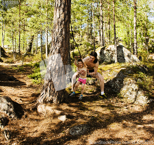 Image of little cute boy jumping with bungee in forest, training with dad