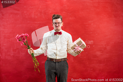 Image of Young funny man with flowers and gift