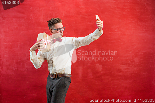 Image of Young beautiful man with gift and phone