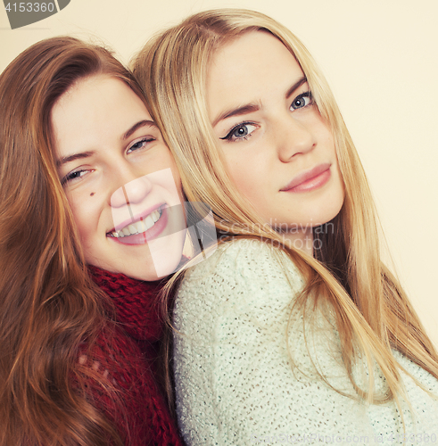 Image of Two young girlfriends in winter sweaters indoors having fun. Lifestyle. Blond teen friends close up