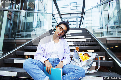 Image of young cute modern indian girl at university building sitting on 