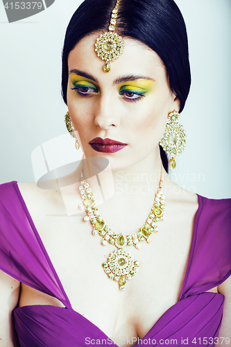 Image of young pretty caucasian woman like indian in ethnic jewelry close up on white, bridal makeup