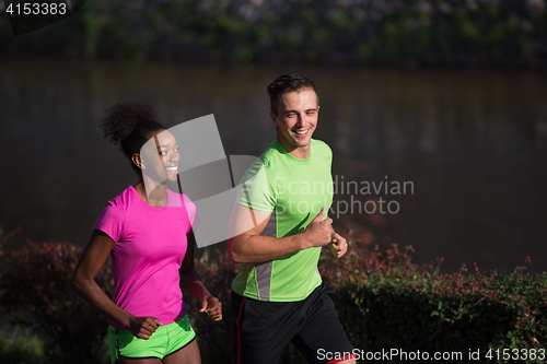 Image of young smiling multiethnic couple jogging in the city