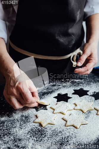 Image of Person putting raw cookies to flour