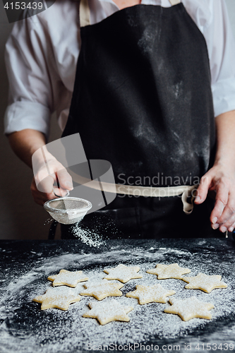 Image of Person putting raw cookies to flour