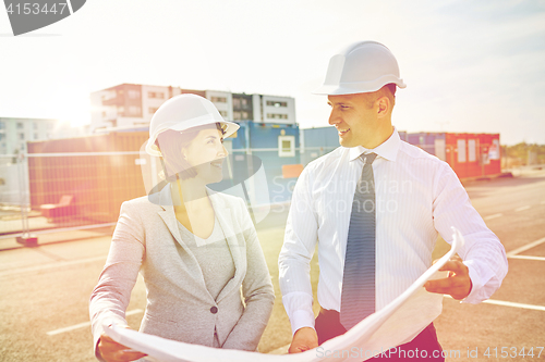 Image of happy architects with blueprint at building