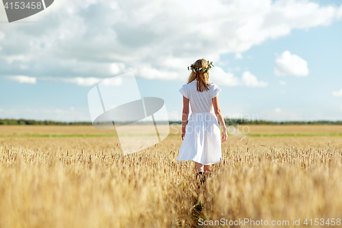 Image of happy young woman in flower wreath on cereal field