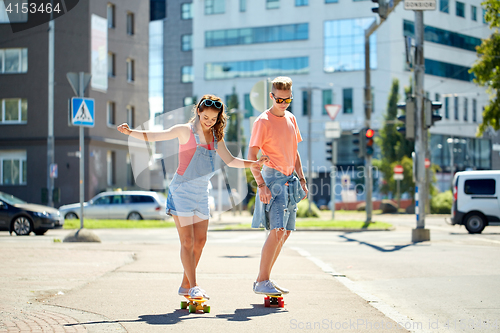 Image of teenage couple riding skateboards on city street