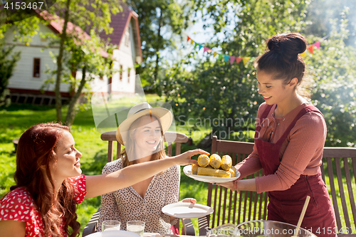 Image of happy friends having dinner at summer garden party