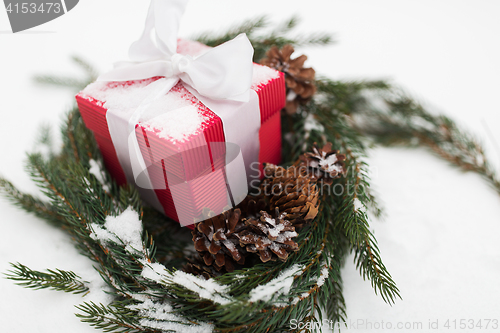 Image of christmas gift and fir wreath with cones on snow