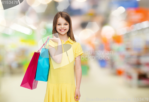 Image of smiling girl with shopping bags over supermarket