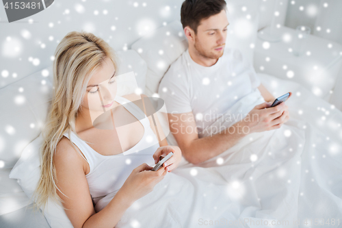 Image of couple with smartphones in bed