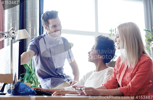 Image of happy creative team with computer in office