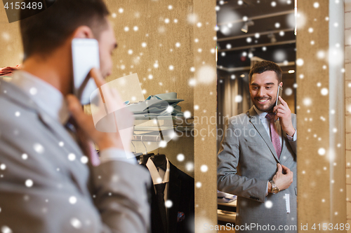 Image of man calling on smartphone at clothing store mirror