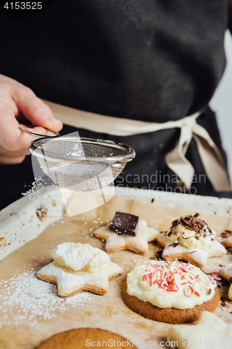 Image of Person decorating cookies with toppings