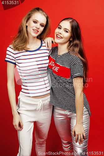 Image of two best friends teenage girls together having fun, posing emotional on red background, besties happy smiling, lifestyle people concept