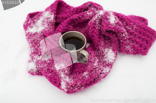 Image of tea or coffee mug and winter scarf on snow