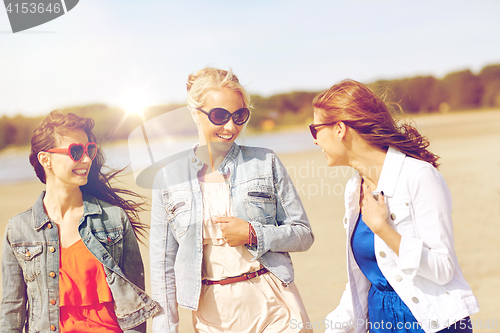 Image of group of smiling women in sunglasses on beach