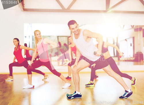 Image of group of smiling people working out with dumbbells