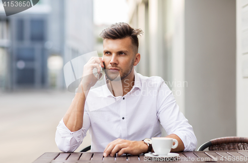 Image of man with coffee calling on smartphone at city cafe