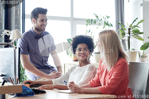 Image of happy creative team talking in office